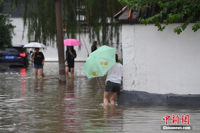 7月31日，市民行走在雨中的北京房山區(qū)瓦窯頭村。北京市氣象臺當日10時發(fā)布分區(qū)域暴雨紅色預(yù)警信號。北京市水文總站發(fā)布洪水紅色預(yù)警，預(yù)計當日12時至14時，房山區(qū)大石河流域?qū)⒊霈F(xiàn)紅色預(yù)警標準洪水。<a target='_blank' href='/'><p  align=