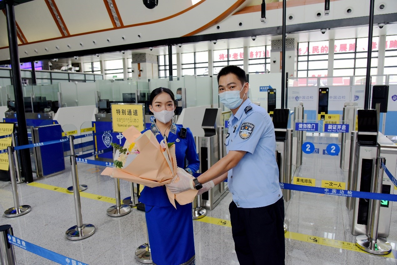 磨憨出入境邊防檢查站民警為中老鐵路第100萬名出入境旅客，D888次國際旅客列車老撾籍乘務員森達拉·妮緹婭（Sengdala Nitiya），送上鮮花。黃遠飛 攝