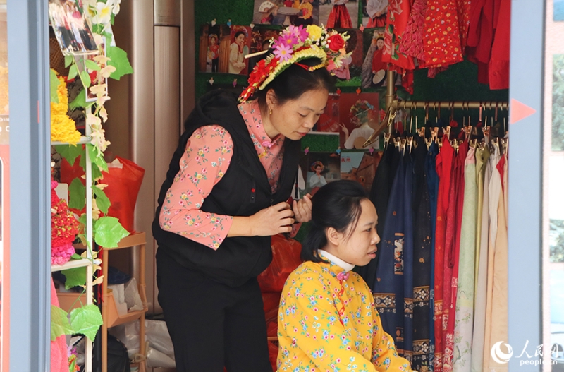 泉州府文廟附近，一名店主正為過(guò)路游客梳理頭發(fā)以佩戴“簪花圍”。人民網(wǎng) 黃東儀攝