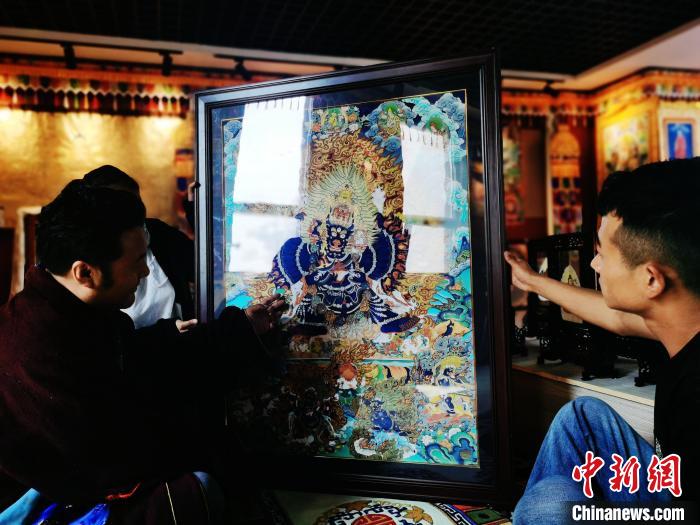 圖為久美尖措(左)與徒弟們展示唐卡作品。　張?zhí)砀?攝