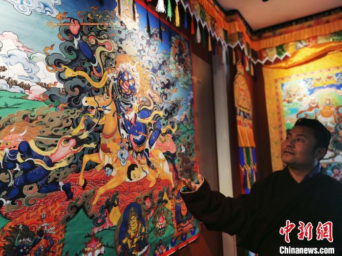 圖為久美尖措展示唐卡作品?！?zhí)砀?攝