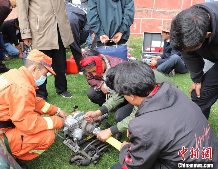 圖為森林消防員為護(hù)林員講解滅火裝備的使用方法?！〔际猩窒乐ш?duì) 供圖