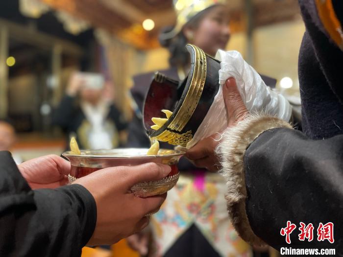 圖為主人在碗中斟滿青稞酒?！∪轿木?攝