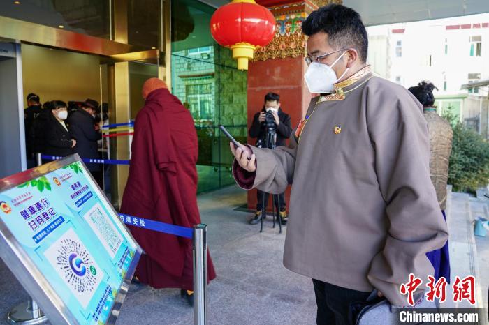 圖為政協(xié)委員掃場所碼進(jìn)入會場?！〗w波 攝