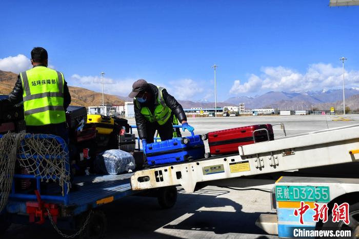 圖為機(jī)場工作人員傳送旅客行李箱?！≈芎?攝
