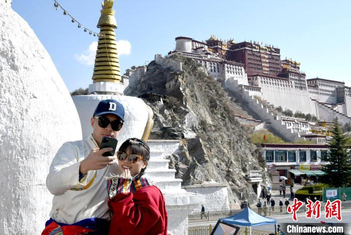 4月17日，游客身著藏式元素服裝在拉薩布達拉宮觀景臺拍照留念。　李林 攝